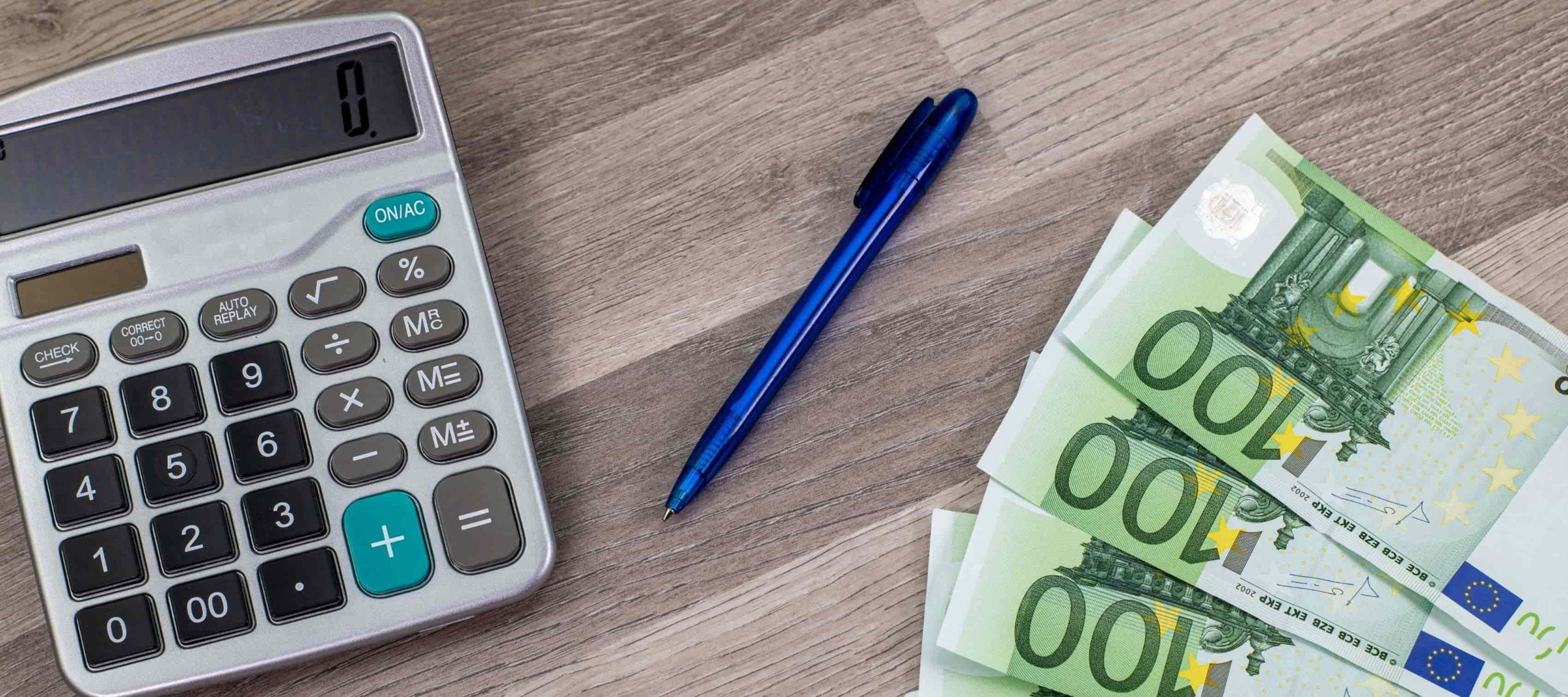 Billetes en euros y calculadora de una persona que está revisando información sobre el impuesto de grandes fortunas