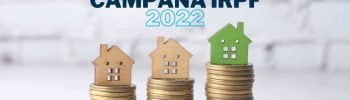 Imagen de casas de madera sobre monedas para hablar acerca de la campaña de la declaración de la renta 2022 en Iniciativa Fiscal.