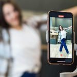 Creadora de contenido grabando un video con un móvil bajo las condiciones de la nueva Ley de Influencers.